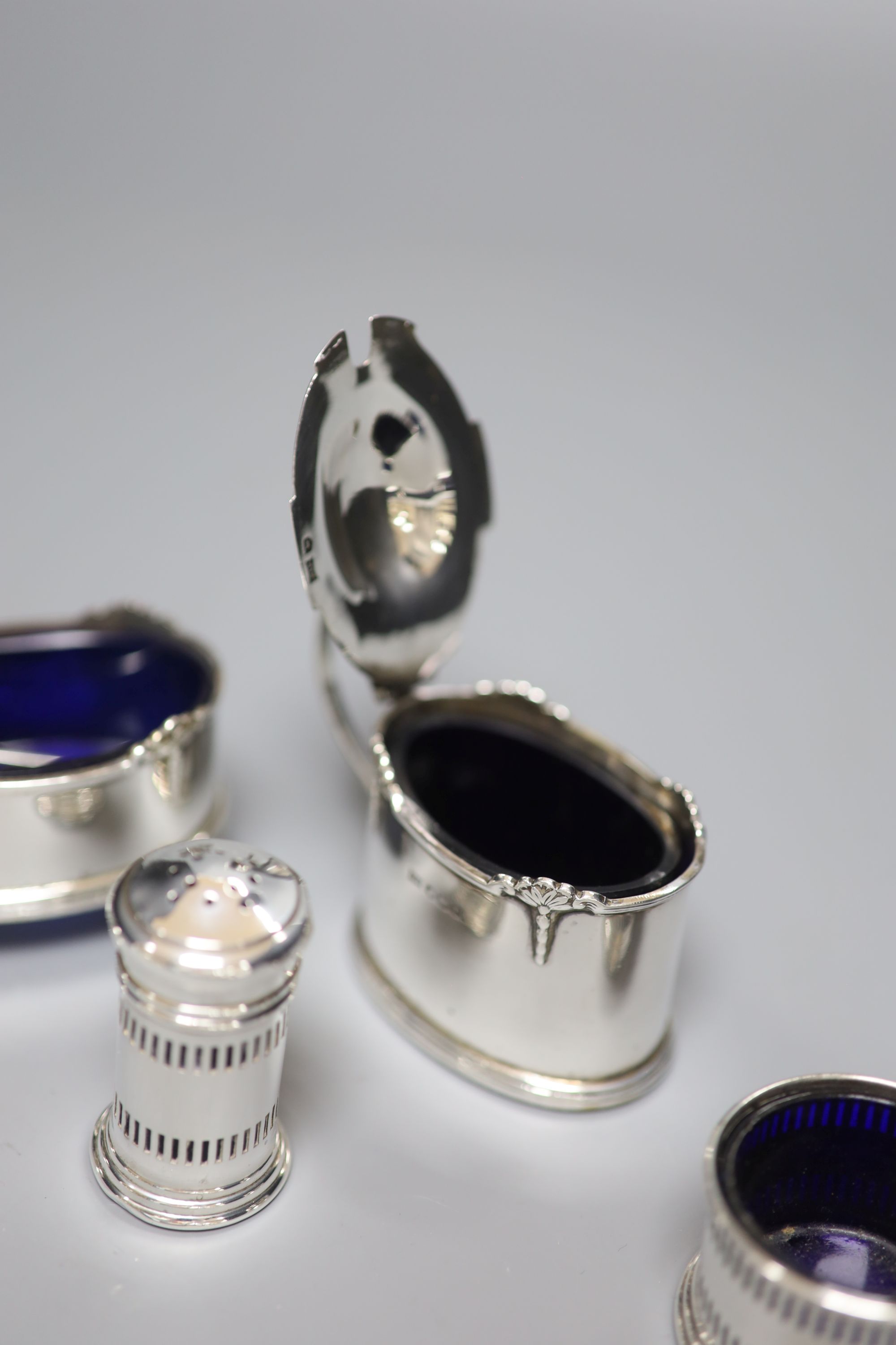 A George V small silver three piece condiment set, Birmingham, 1932 and two other silver condiments.
